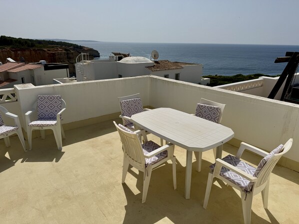 Een terras met een tafel en stoelen, met uitzicht op de zee.