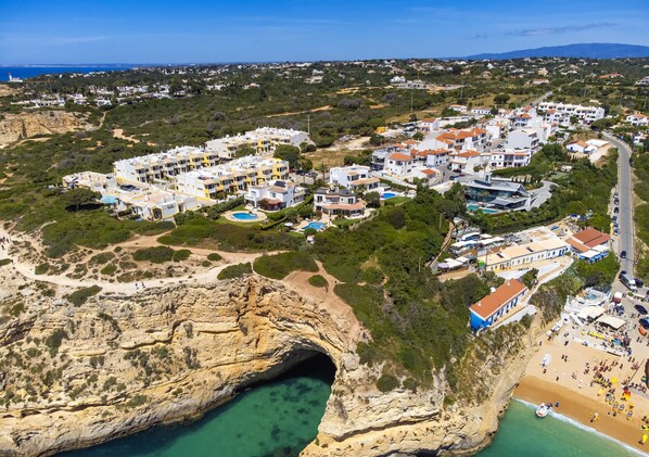Vue aérienne d’une ville côtière, avec une falaise rocheuse imposante, une plage et un port de plaisance.
