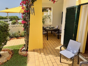 A patio with a table and chairs, a yellow wall, and a green shutter. - 21 Terraços de Benagil (Casa Mars) (Benagil)