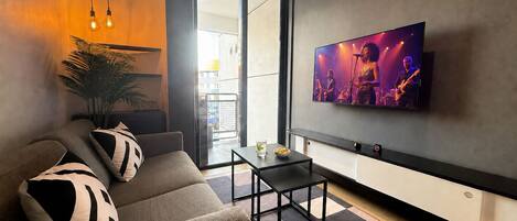 A modern living room with a sofa, a coffee table, and a flat-screen TV mounted on the wall.