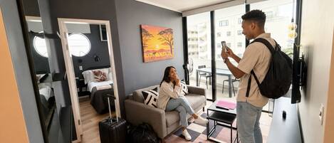 A modern living room with a sofa, a coffee table, and a large window offering a view of the city.