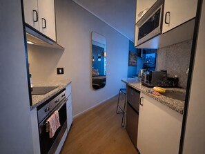 Cocina compacta con microondas, cafetera y una pequeña isla.