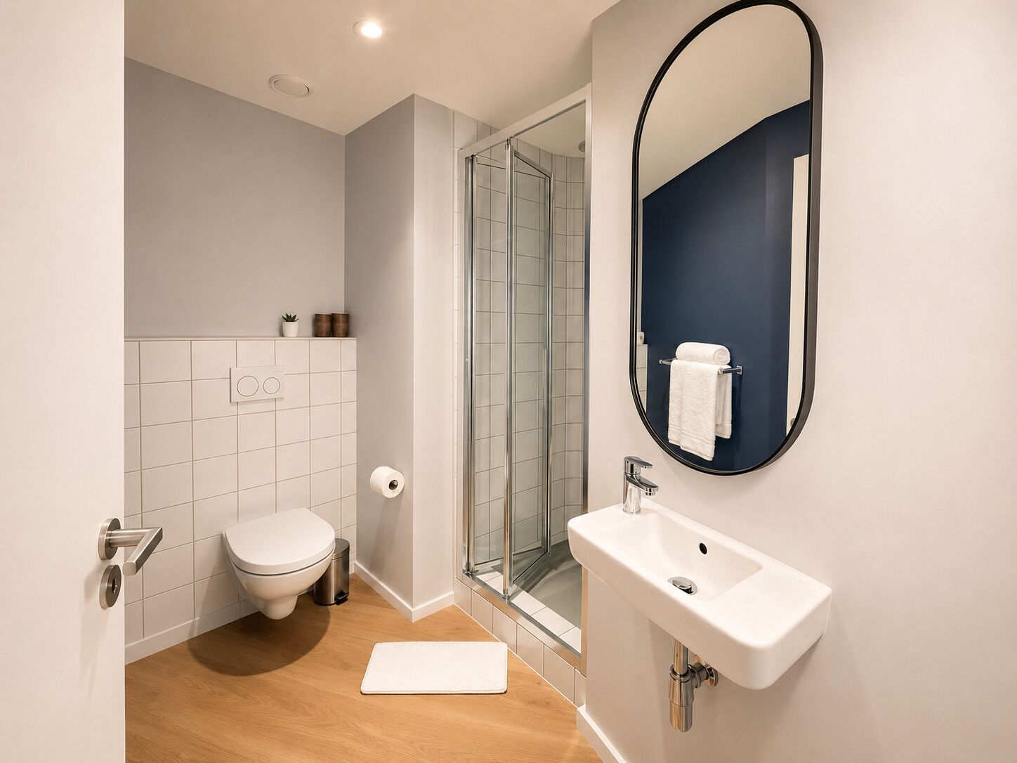 Et moderne badeværelse med toilet, vask og brusebad.