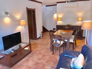 A living room with a TV, sofa, dining table, and chairs. - 45 Terraços de Benagil (Casa Céu Azul) (Benagil)