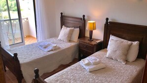 A hotel room with two beds, each with a wooden headboard, white linens, and a bedside table with a lamp. - 45 Terraços de Benagil (Casa Céu Azul) (Benagil)