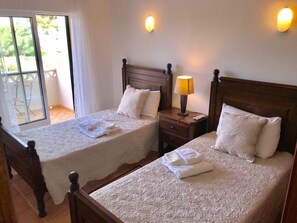 A hotel room with two beds, each with a wooden headboard, white linens, and a bedside table with a lamp. - 45 Terraços de Benagil (Casa Céu Azul) (Benagil)