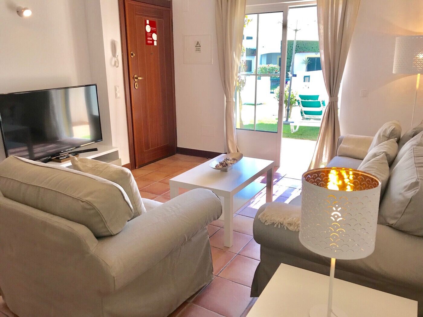 A living room with a TV, two sofas, a coffee table, and a lamp.