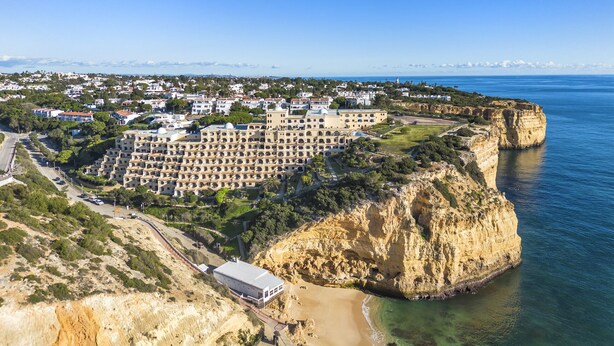 An aerial view of a coastal hotel with multiple buildings, a beach, and cliffs. - Casa Colina Sol 611 - Seaview apartment (Carvoeiro)
