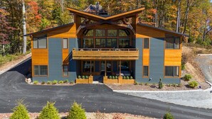 Une maison de style moderne, construite en bois sur deux étages, avec une façade en bois remarquable, de grandes fenêtres et un balcon.