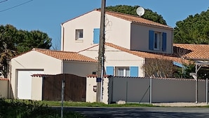 A two-story house with a tiled roof, a satellite dish, and a gated driveway. - Quiet family home 10 minutes walk from the sea (Dolus-d'Oléron)