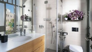 Ein modernes Badezimmer mit Duschkabine aus Glas, einer weißen Toilette und einem Waschtisch mit Spiegel.