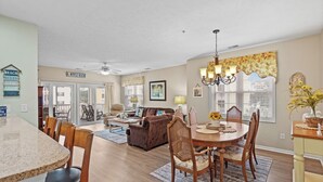 A spacious living room with a fireplace, a dining area with a round table, and a kitchen with a granite countertop.