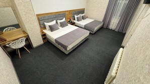 Ein Hotelzimmer mit zwei Betten, einem Schreibtisch, einem Stuhl und einem fenster mit Vorhängen.