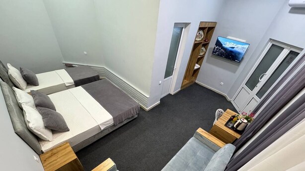 Ein kleines Hotelzimmer mit Bett, einer Couch, einem kleinen Tisch und einem an der Wand montierten Fernseher.