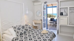 Quarto com cama, mesa de cabeceira e vista para o exterior.
