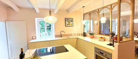 A modern kitchen with a central island, a built-in oven, and a large window providing natural light.