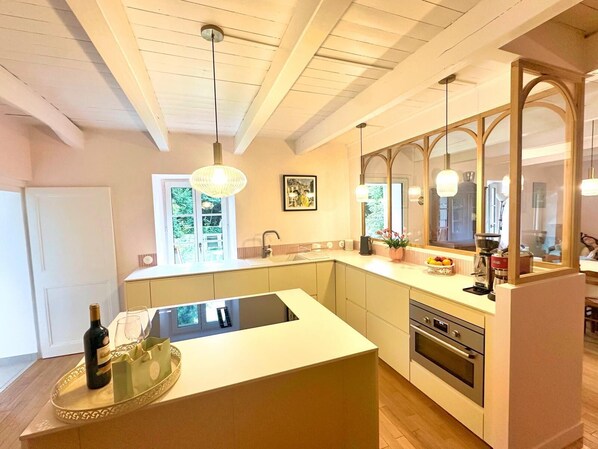 A modern kitchen with a central island, a built-in oven, and a large window providing natural light.