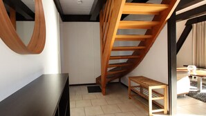 A modern interior with a wooden staircase, a dark wooden bench, and a small wooden table. - Nurdachhaus in Burhave (Butjadingen)