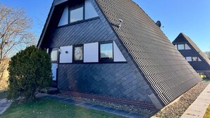 A modern house with a unique triangular roof design, large windows, and a satellite dish. - Nurdachhaus in Burhave (Butjadingen)