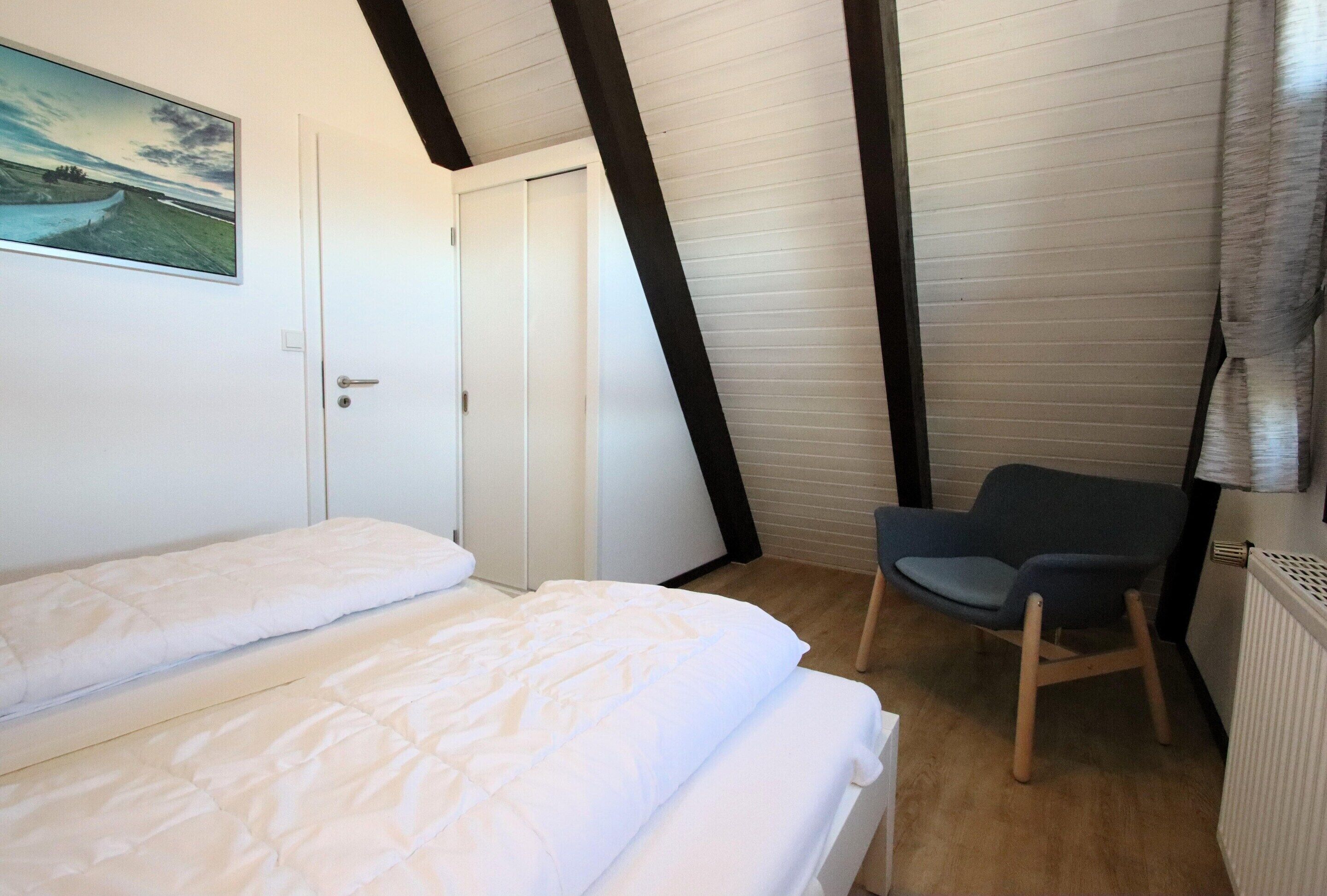 Une chambre à coucher avec un lit, une chaise, une porte et un tableau au mur.