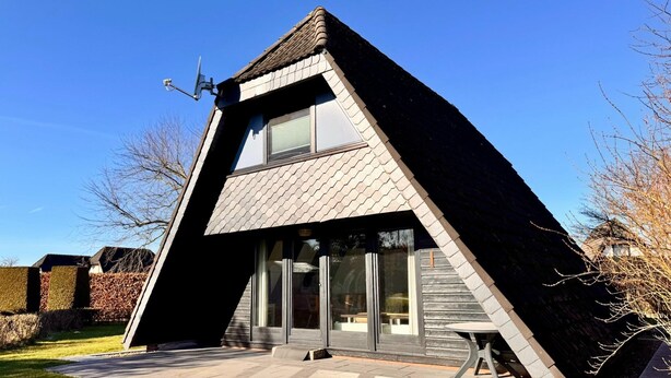 A modern house with a triangular roof, large windows, and a satellite dish. - Nurdachhaus in Burhave (Butjadingen)