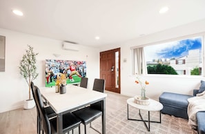 Ein modernes Wohnzimmer mit Essbereich, einem großen Fenster mit Blick und einem sportbezogenen Kunstwerk an der Wand.