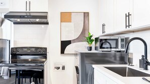 A modern kitchen with a stainless steel range, a microwave, and a sink. - Modern 2BR • Near DT + Stadiums • Parking (Seattle)