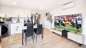 A modern kitchen with white cabinets, a stainless steel refrigerator, and a dining area with a table and chairs. - Modern 2BR • Near DT + Stadiums • Parking (Seattle)