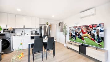 Een moderne keuken met witte kasten, een roestvrijstalen koelkast en een eethoek met een tafel en stoelen.