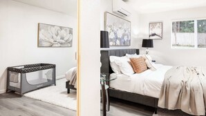 A bedroom with a bed, bedside table, and a crib.