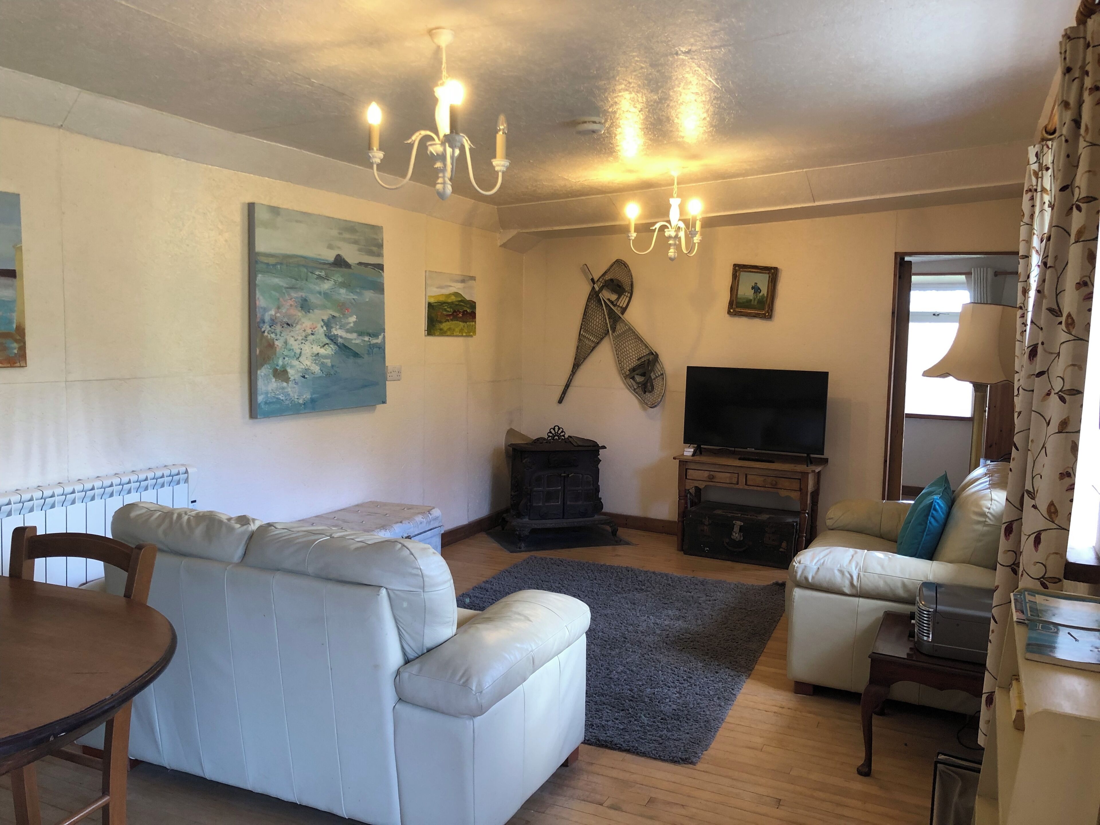 A living room with a sofa, a television, a fireplace, and a painting on the wall.