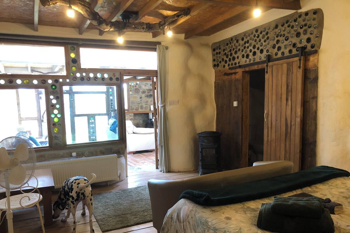 Una habitación acogedora con una cama, techo de madera, pared de piedra y ventana con vistas.