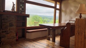 A rustic room with a stone wall, wooden bench, and a table. - Monument Field South Brent (South Brent)