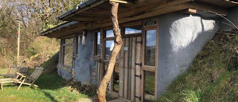 Una cabaña rústica con techo inclinado, ventanas grandes y chimenea.