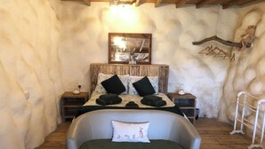 A cozy bedroom with a bed, a bedside table, a lamp, and a hanging wooden decoration. - Monument Field South Brent (South Brent)