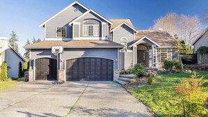 Une maison à deux étages avec un garage, une pelouse devant et une allée.