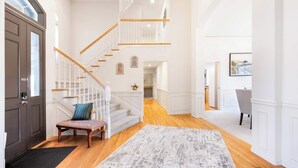 Un hall d’entrée spacieux avec un grand escalier, un banc et un grand tapis.