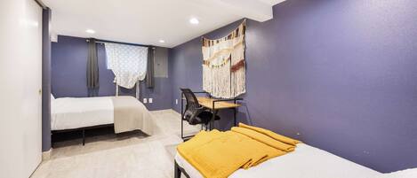 A room with two beds, a desk, and a chair.