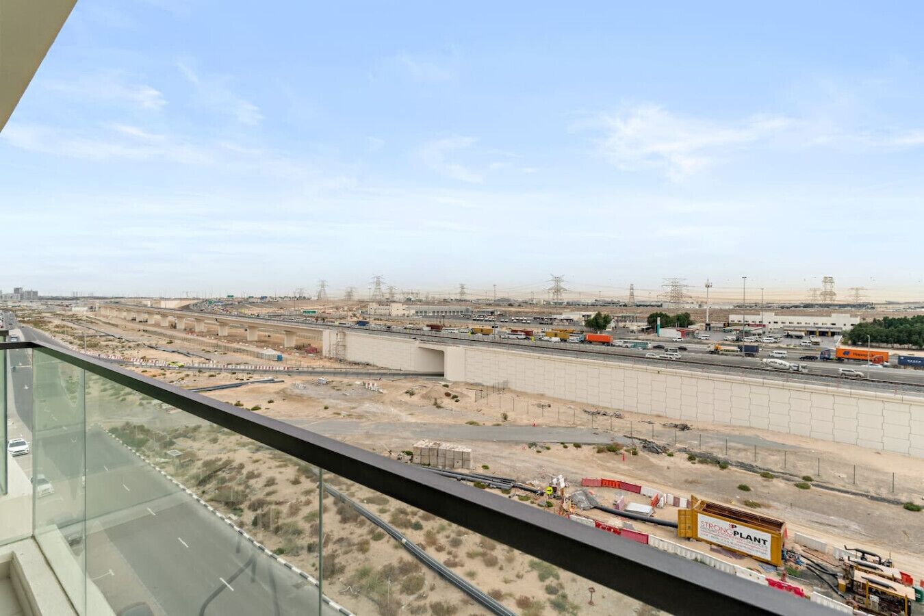 A view from a high-rise window overlooking a highway with multiple lanes, a bridge, and industrial buildings.