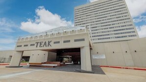 A building with a sign reading "TEAK" and a large glass structure in front. - Chic 1-bedroom apartment with fitness room and AC in vibrant Houston (Houston)