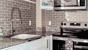 A kitchen with white cabinets, a stainless steel microwave, a built-in oven, and a granite countertop. - Chic 1-bedroom apartment with fitness room and AC in vibrant Houston (Houston)