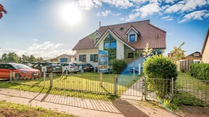 En boligbygning med tegltag, en indhegnet have og parkerede biler.
