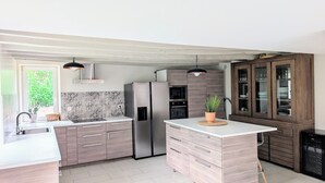 A modern kitchen with a central island, stainless steel appliances, and a wooden cabinet with glass doors.