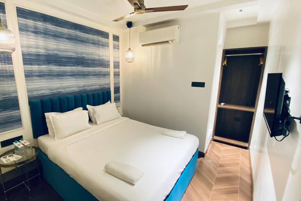 Una habitación de hotel moderna con una cama grande, un cabecero azul y vistas al océano a través de la ventana.