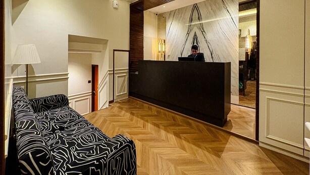 Un vestíbulo de hotel con una recepción, un sofá estampado y un suelo de madera con diseño de espiga.