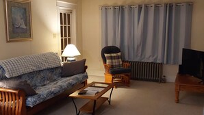 Ein Wohnzimmer mit einer Couch, einem Sessel, einem Couchtisch und einem Fernseher.