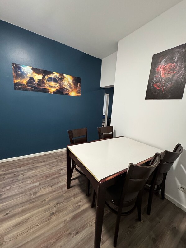 Ein Essbereich mit dunkelblauer Wand, einem weißen Tisch und Holzsesseln.