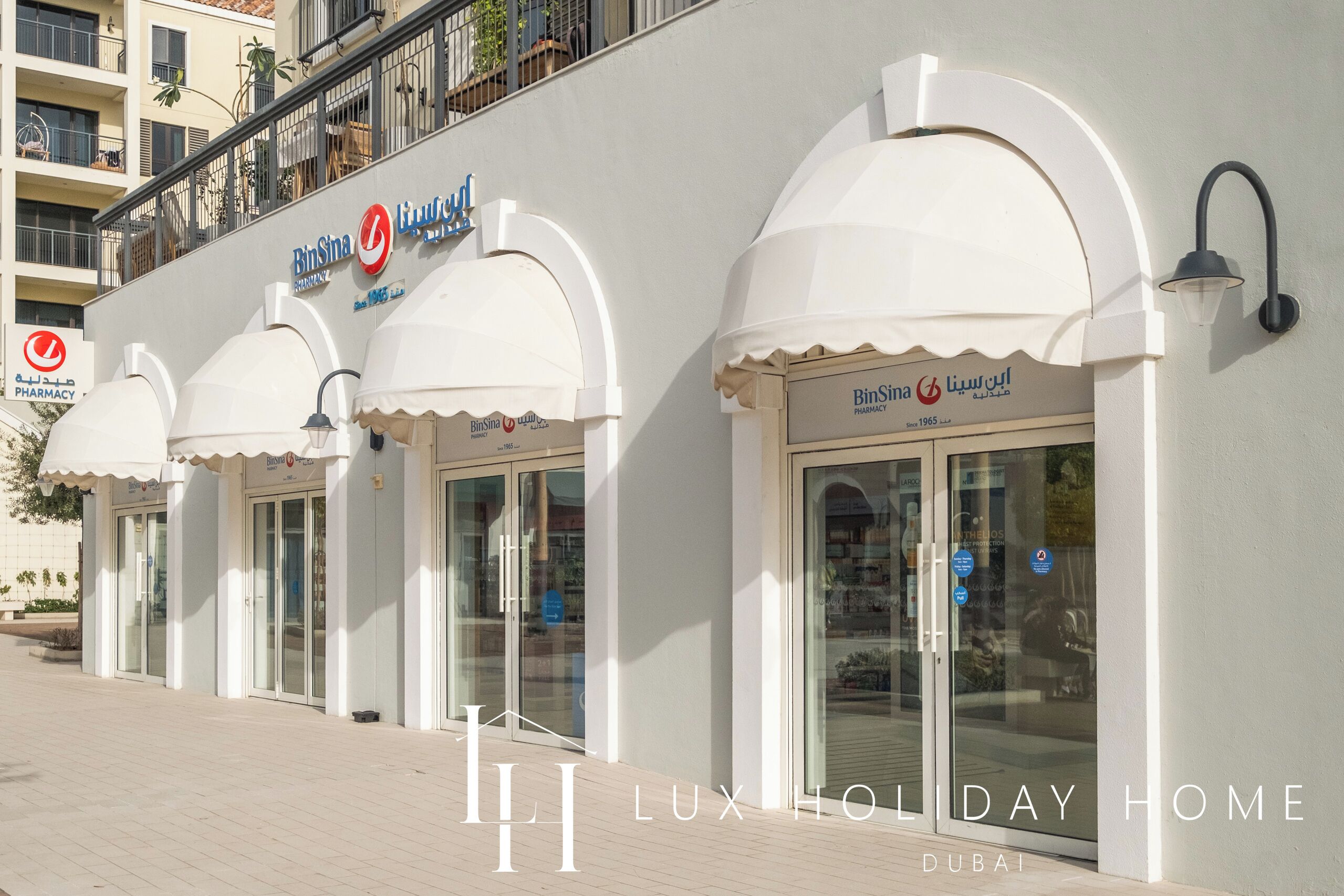 A building with multiple storefronts, including a pharmacy named BinSina.