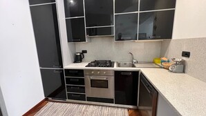 A compact kitchen with black cabinets, a gas stove, a sink, and a small countertop area.