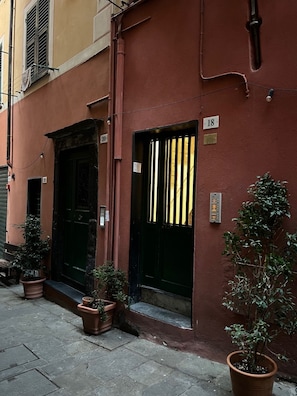 Traditional buildings line the narrow cobblestone street, each with its own entrance and potted plants.